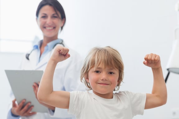 Happy child next to a doctor in hospital ward